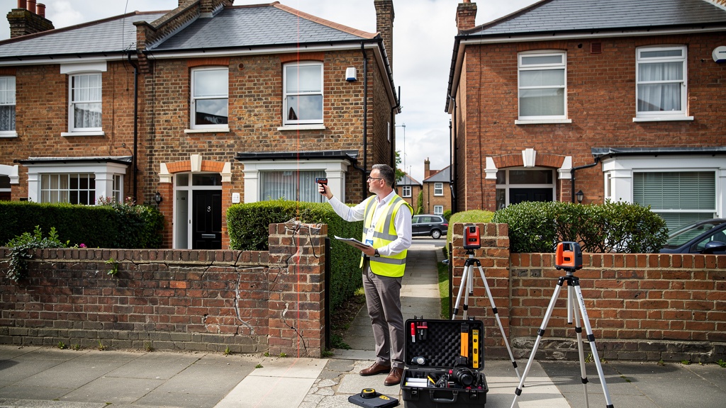 Professional party wall surveyor inspecting shared boundary wall between two terraced houses